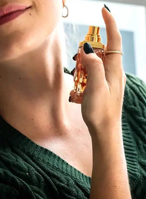 caucasian woman applying perfume her neck copia